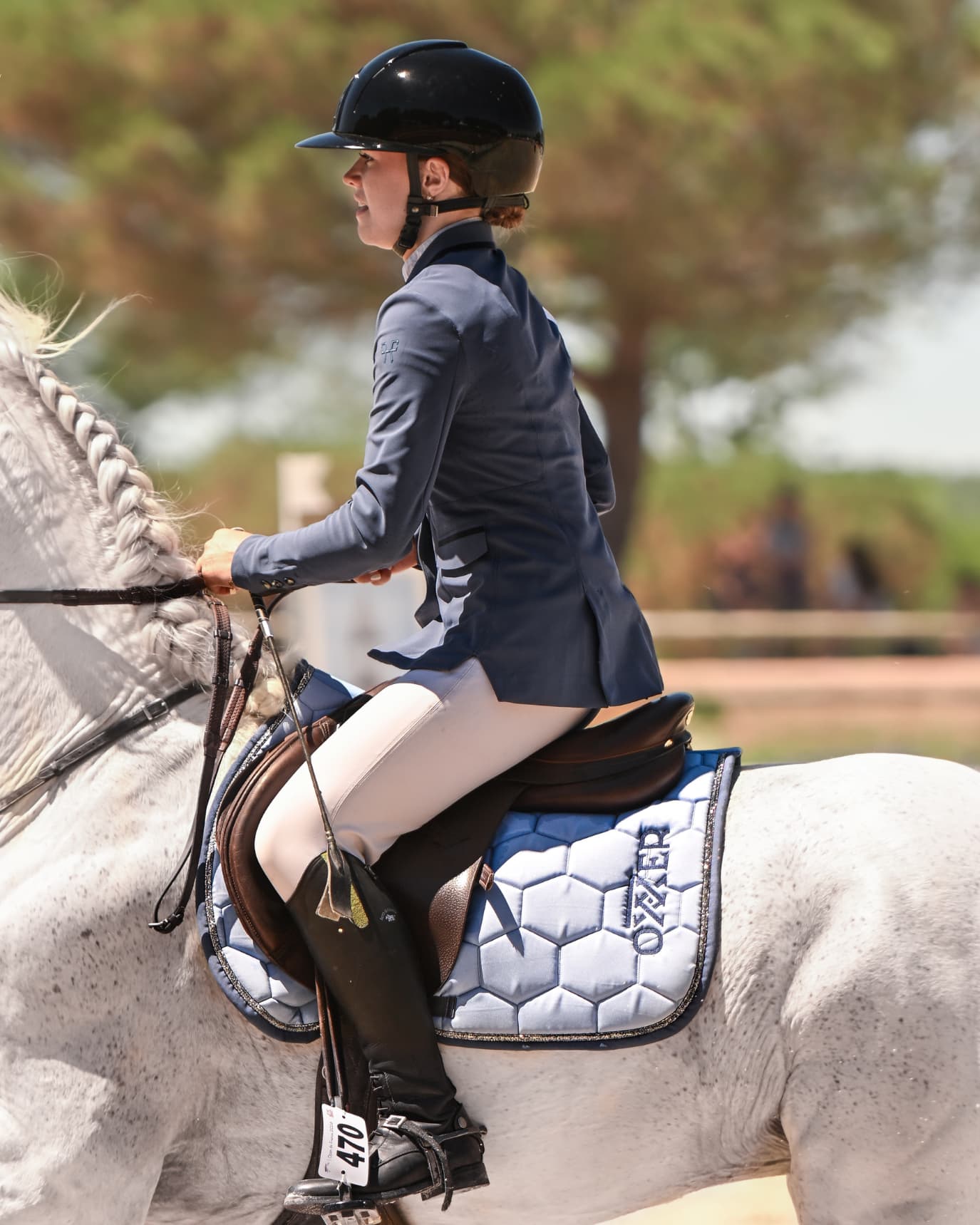 Veste de concours indigo portée par une cavalière en piste